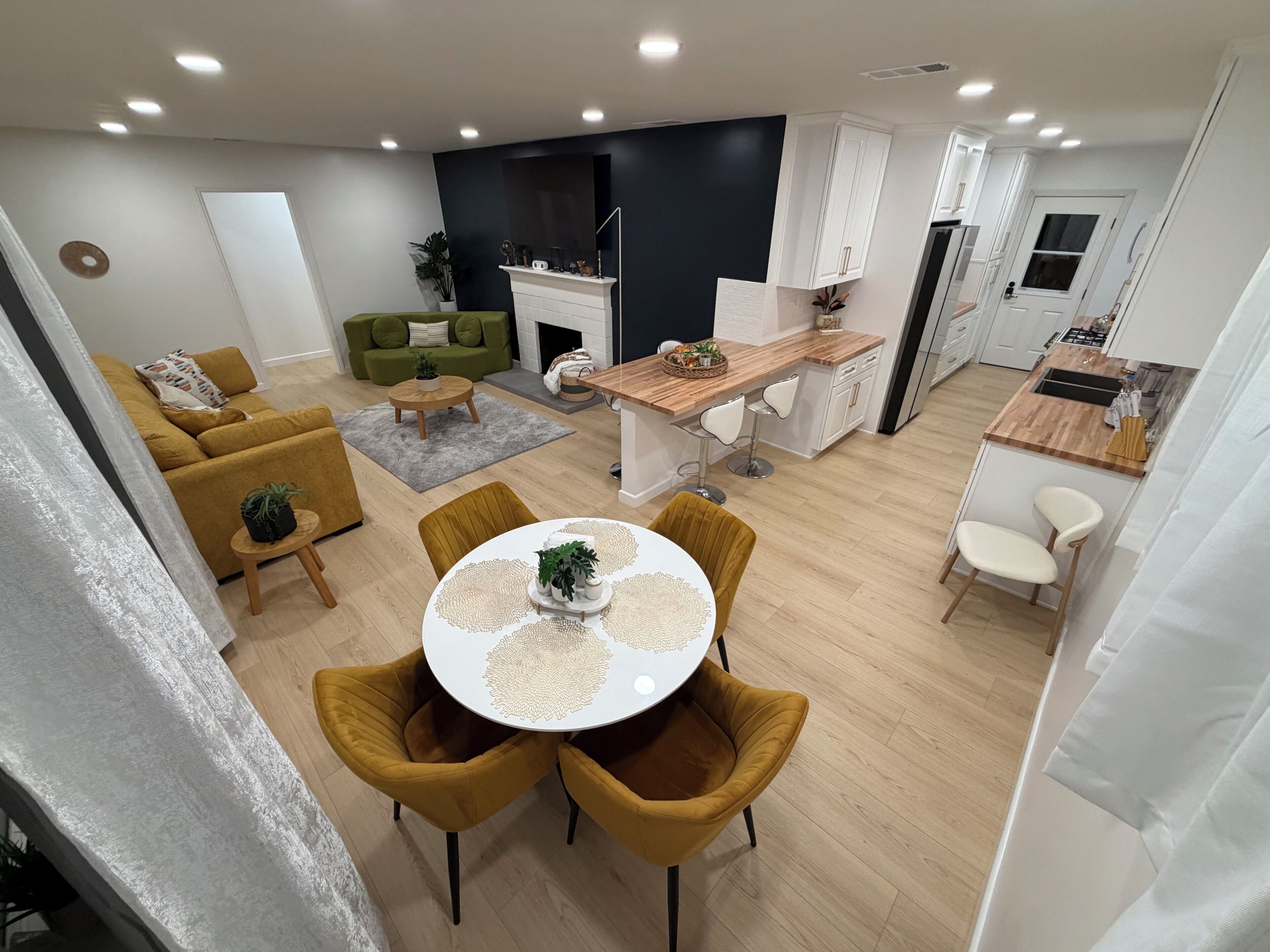 Un espace de vie moderne comprenant un coin repas, une cuisine et un canapé vert.