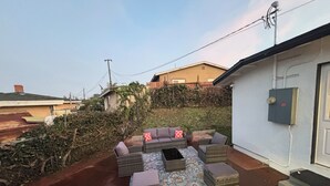 A patio with outdoor furniture, a patterned rug, and a house in the background. - Your Ideal Stay Near Disney (Placentia)