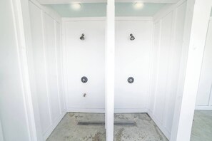 A white bathroom with two showerheads and a drain. - 6BR, POOL, 2 min walk to beach, Oceanview, Game Rm (Carolina Beach)
