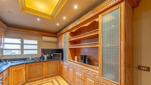 A kitchen with wooden cabinetry, a microwave, and a window.