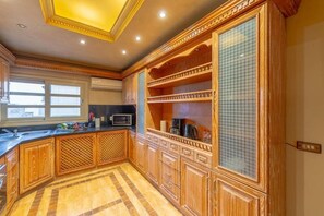 A kitchen with wooden cabinetry, a microwave, and a window.
