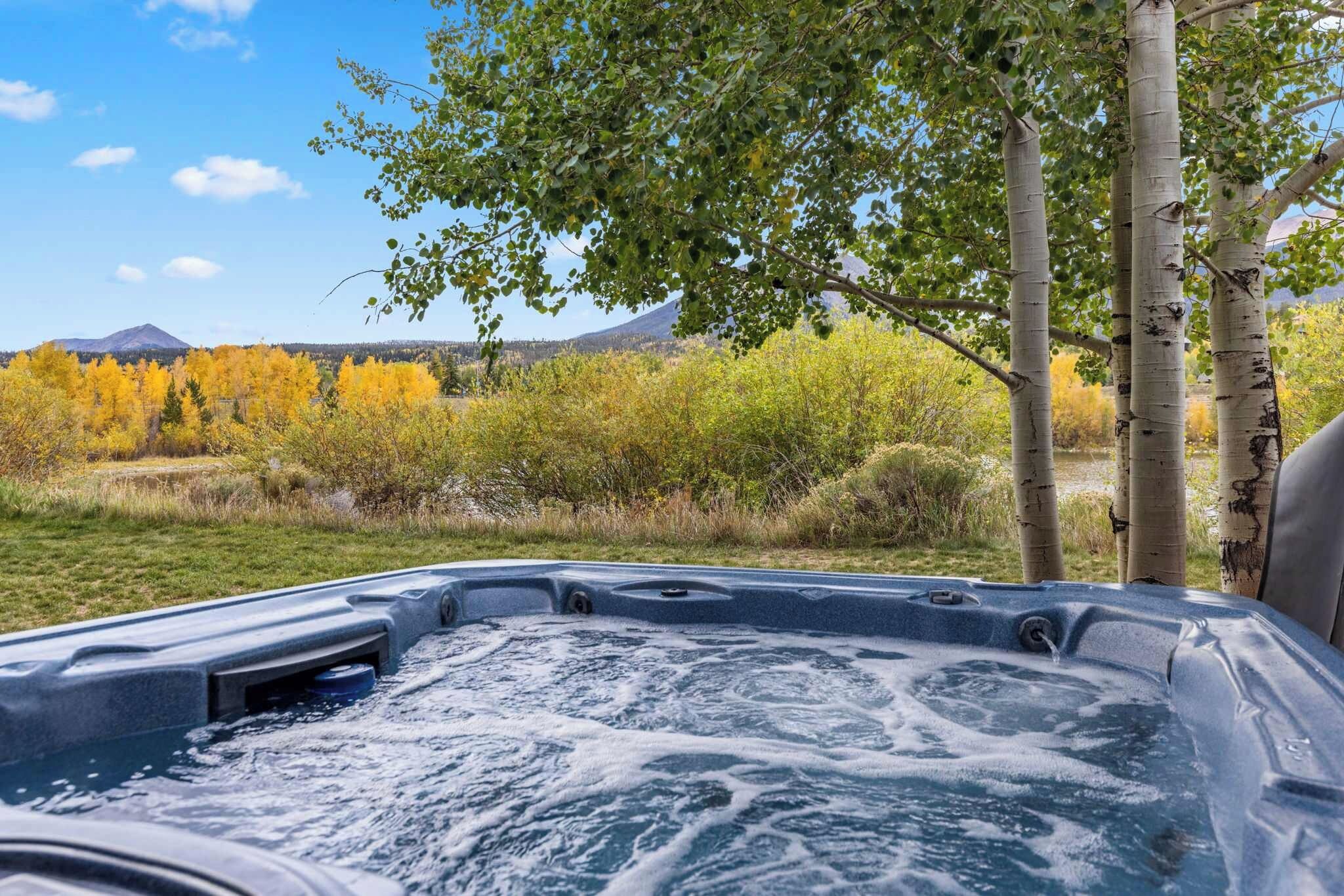 A hot tub with a view of a mountainous landscape and autumn foliage.