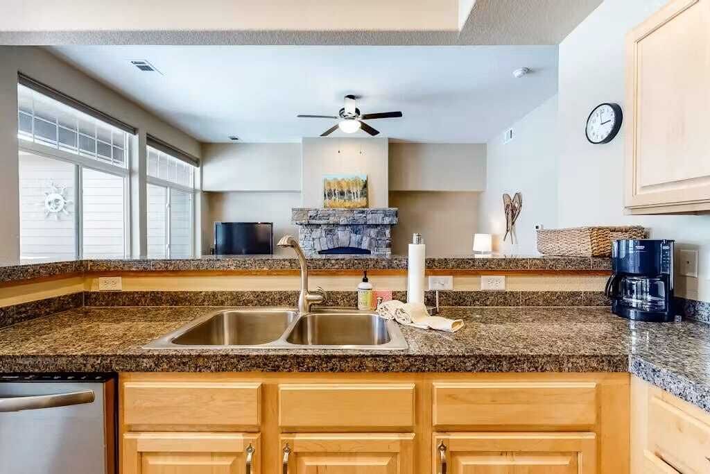 A kitchen with granite countertops, wooden cabinets, a built-in stove, and a ceiling fan.