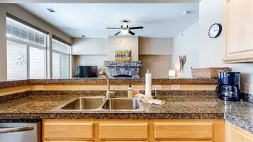 A kitchen with granite countertops, wooden cabinets, a built-in stove, and a ceiling fan.