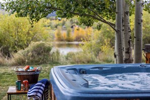 A hot tub with a view of a lake and trees in the background.