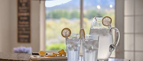A kitchen counter with a pitcher of water, glasses, and orange slices.