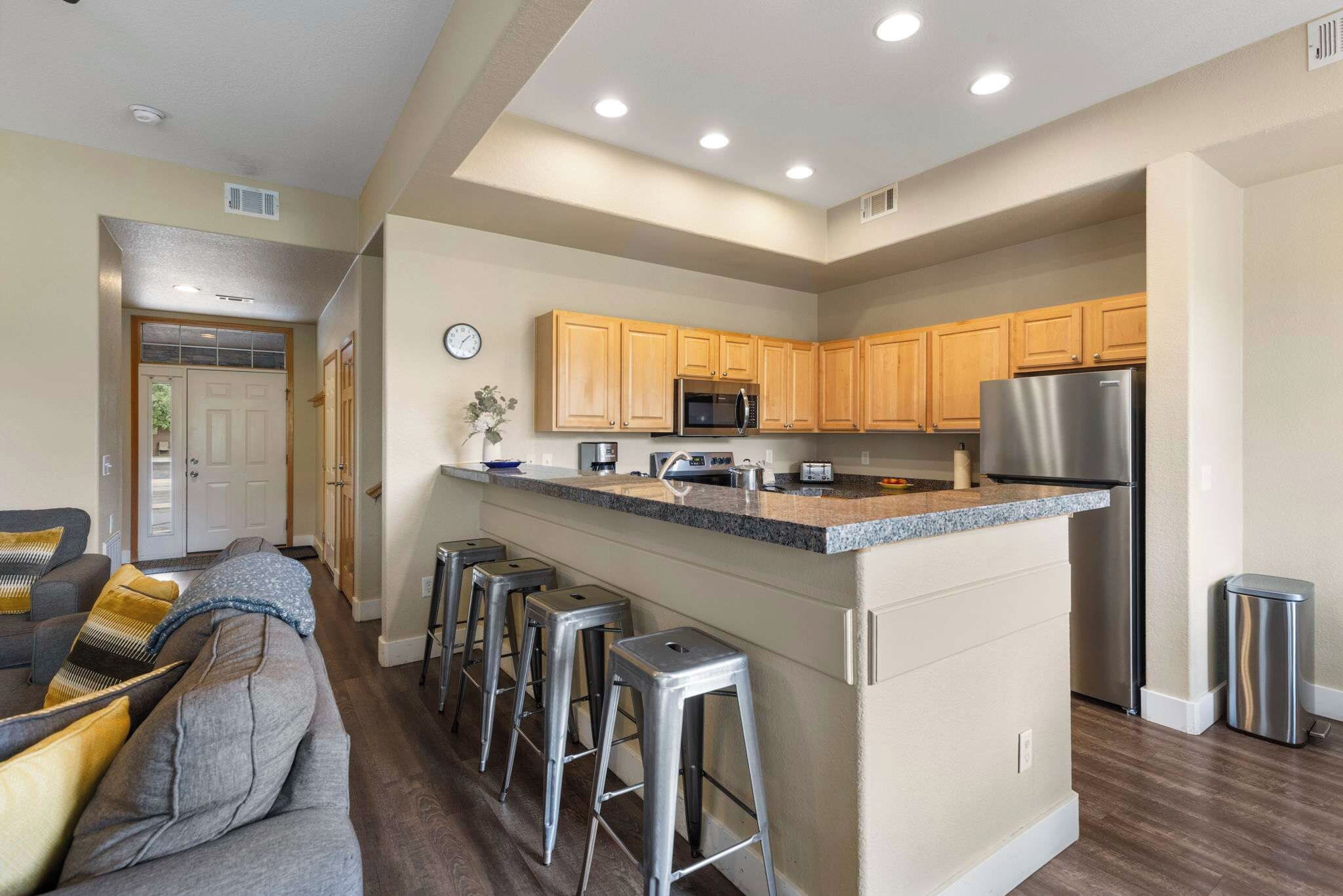 A modern kitchen with wooden cabinets, stainless steel appliances, and a central island with bar stools.