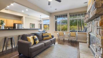 A modern living room with a gray sofa, two armchairs, and a stone fireplace.