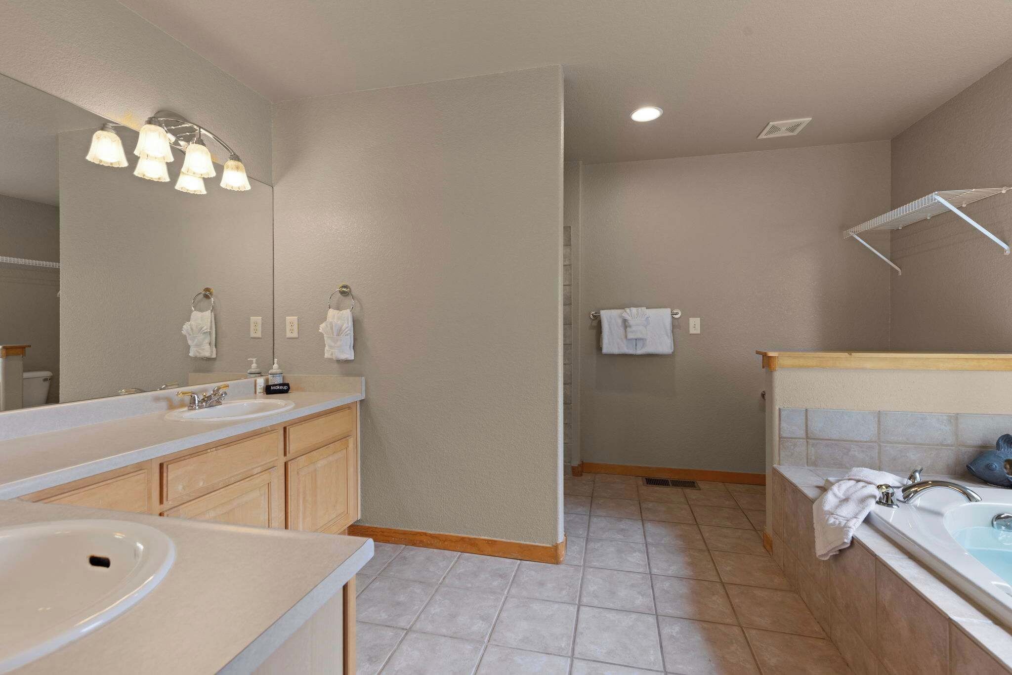 A bathroom with a double sink vanity, a mirror, a towel rack, and a shower area.