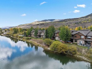 A residential area with houses along a river, surrounded by hills.