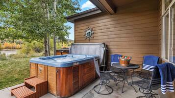 A hot tub with steps, a table, chairs, and a sun decoration on a wooden wall.