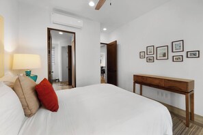 Ein Hotelzimmer mit einem großen Bett, einem Nachttisch mit Lampe, einem Holzkonsole und einer Wand mit gerahmten Bildern.