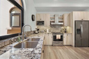 A modern kitchen with a double sink, stainless steel appliances, and a patterned backsplash. - Mavila Luxury Condo | Golf, Spa & Quvira Lifestyle (Cabo San Lucas)