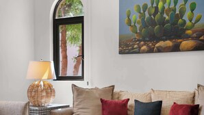 Ein Wohnzimmer mit einer Couch, Kissen, einer Lampe und einem Kakteenbild an der Wand.