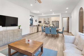 A modern living room with a flat-screen TV, a wooden coffee table, and a sofa. - Mavila Luxury Condo | Golf, Spa & Quvira Lifestyle (Cabo San Lucas)