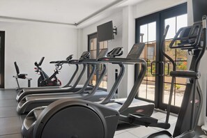Ein Fitnessraum mit mehreren Laufbändern, Ergometer und einem Bildschirm.