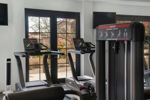 A gym with treadmills, an elliptical, and a steamer. There are windows with a view of the outside. - Mavila Luxury Condo | Golf, Spa & Quvira Lifestyle (Cabo San Lucas)