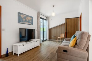 Ein modernes Wohnzimmer mit Flachbildfernseher, einer Couch, einem kleinen Beistelltisch und einer Weltkarte an der Wand.