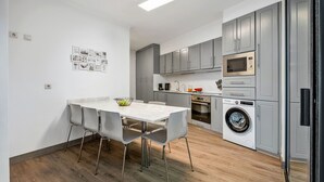 Une cuisine moderne avec des meubles gris, un four à micro-ondes encastré et un lave-linge.