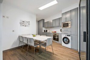 A modern kitchen with grey cabinets, a built-in microwave, and a washing machine. - Villa Brava Sunset by Homie (Ribeira Brava)
