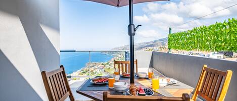 Balcón con una mesa dispuesta para el desayuno, con vista al mar.