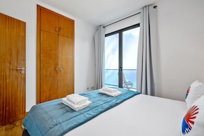 A hotel room with a bed, a wardrobe, and a balcony with a view. - Villa Brava Sunset by Homie (Ribeira Brava)