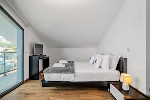 Ein modernes Schlafzimmer mit einem großen Bett, einem Schreibtisch und einem Fernseher.