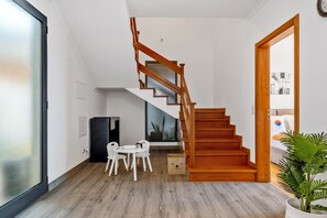 A modern interior with a wooden staircase, a dining area with a table and chairs, and a large window. - Villa Brava Sunset by Homie (Ribeira Brava)