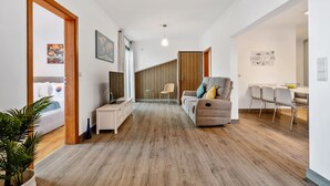 Un salon moderne avec un canapé, un coin repas avec des chaises et une cuisine visible au fond.