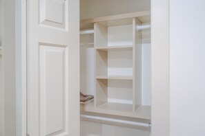 Ein Schrank mit geöffneten Türen, der Regale und ein gefaltetes Kleidungsstück zeigt.