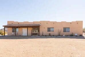 A single-story building with a flat roof, a covered patio, and a desert landscape. - Queen of the Desert, 2 acres with expansive views (Joshua Tree)