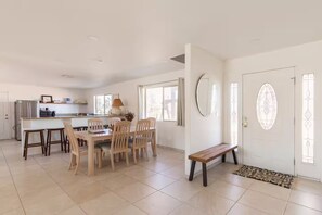 A spacious kitchen with a dining area, a bench, and a door with decorative glass panels. - Queen of the Desert, 2 acres with expansive views (Joshua Tree)