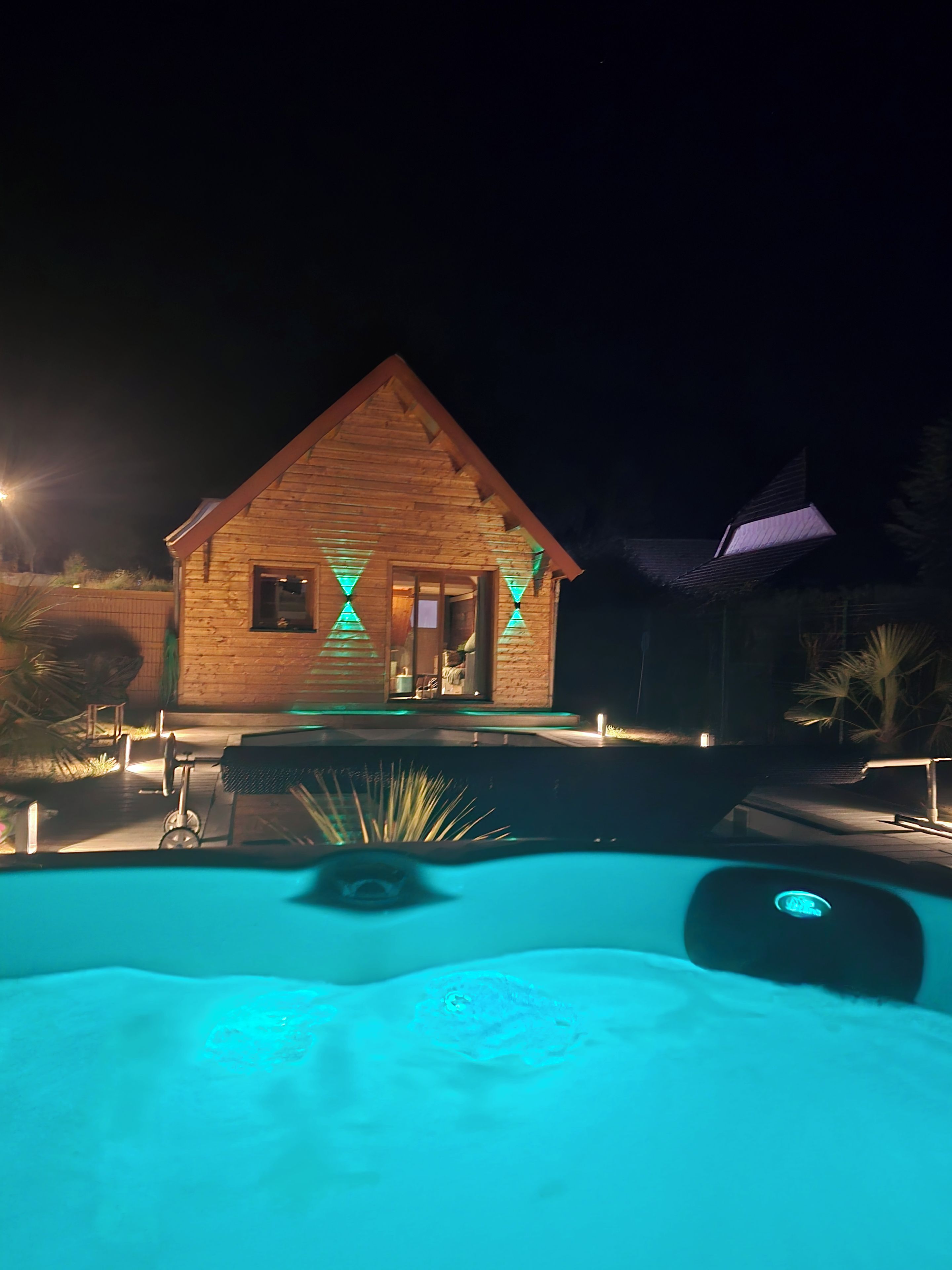 Eine Holzhütte mit Pool bei Nacht.