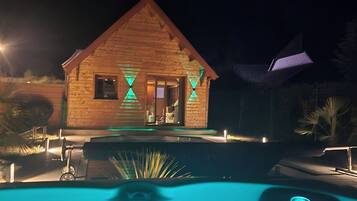 Eine Holzhütte mit Pool bei Nacht.