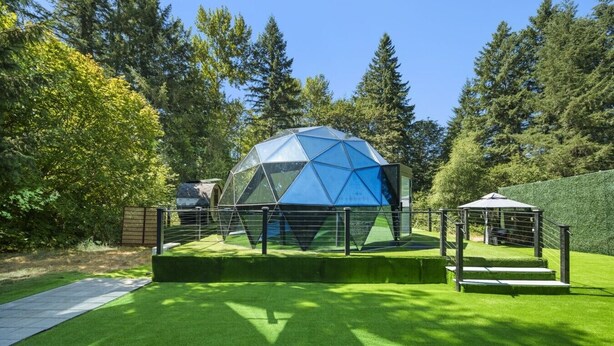 A geodesic dome structure with a surrounding fence and a small pavilion in a landscaped area with grass and trees. - Evergreen Escape | Private Glass Dome, Sauna & Forest Views (Redmond)