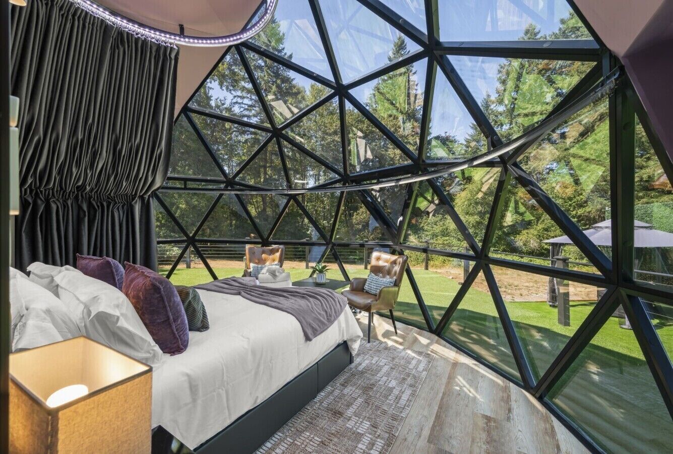 Thoughtfully furnished interior with a cozy bed, seating area, and floor-to-ceiling panoramic views.