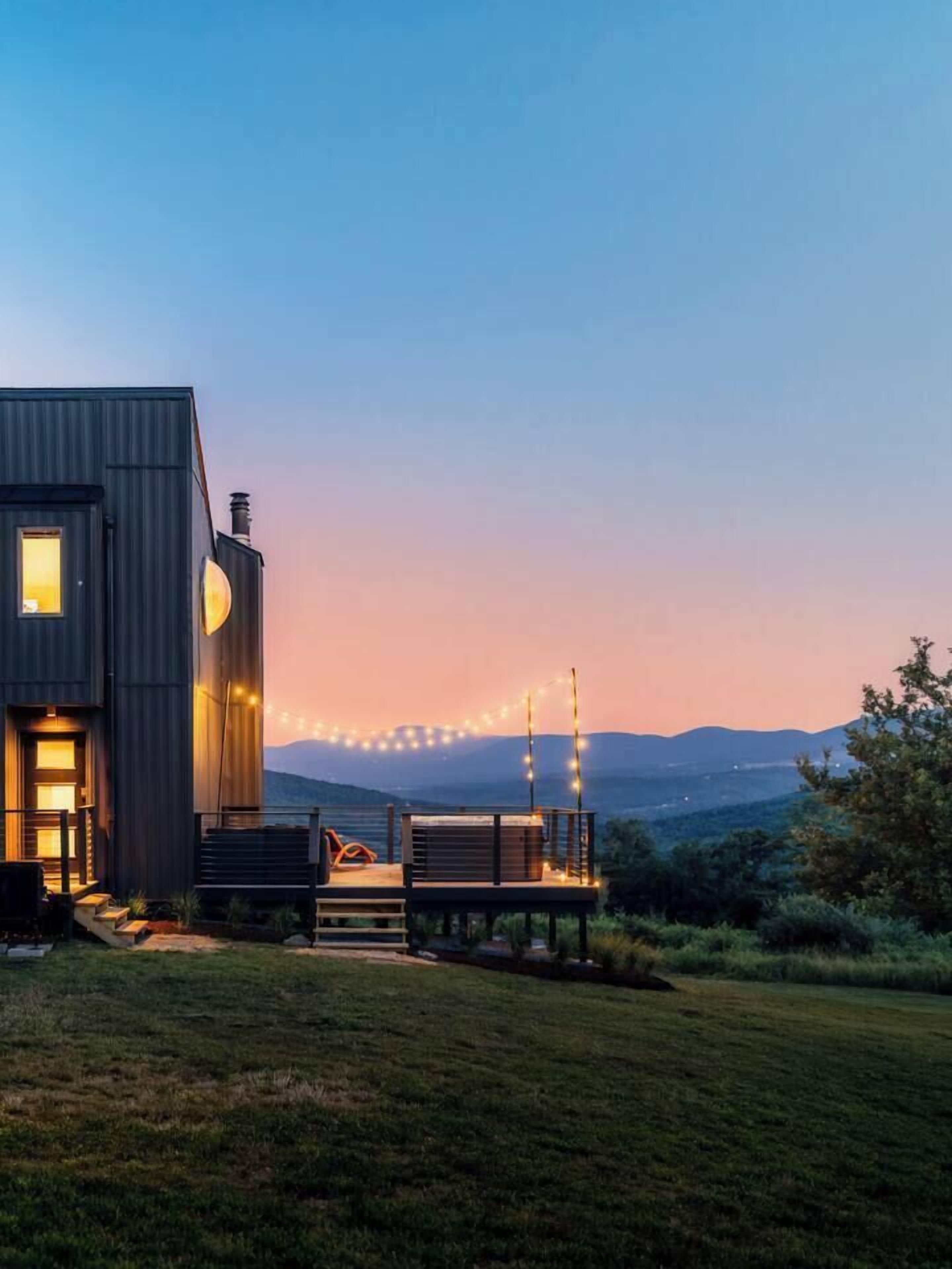 Een modern huis met een terras en lichtjes.