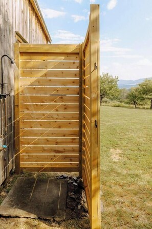 Una porta de fusta que dona a una zona exterior coberta, amb una porta metàl·lica i un petit graó.