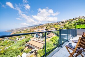 A balcony with a view of a coastal town, including houses and the sea. - Villa Brava Sunset by Homie (Ribeira Brava)