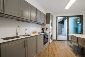 A modern kitchen with grey cabinets, stainless steel appliances, and a wooden floor. - Villa Brava Sunset by Homie (Ribeira Brava)