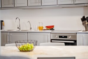 A modern kitchen with a stainless steel sink, a fruit bowl, and a digital oven display. - Villa Brava Sunset by Homie (Ribeira Brava)