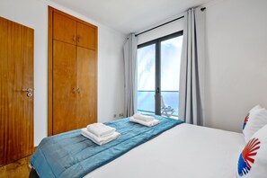 A hotel room with a bed, a wardrobe, and a window with curtains. - Villa Brava Sunset by Homie (Ribeira Brava)
