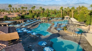 Un resort con varias piscinas, tumbonas y sombrillas.
