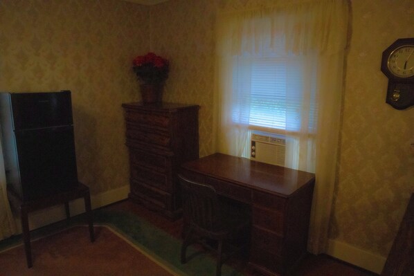 Una habitación con un escritorio de madera, una silla, un aparador y un reloj en la pared.