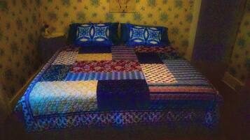 A bed with a patchwork quilt, a headboard, and a wall with a floral pattern.