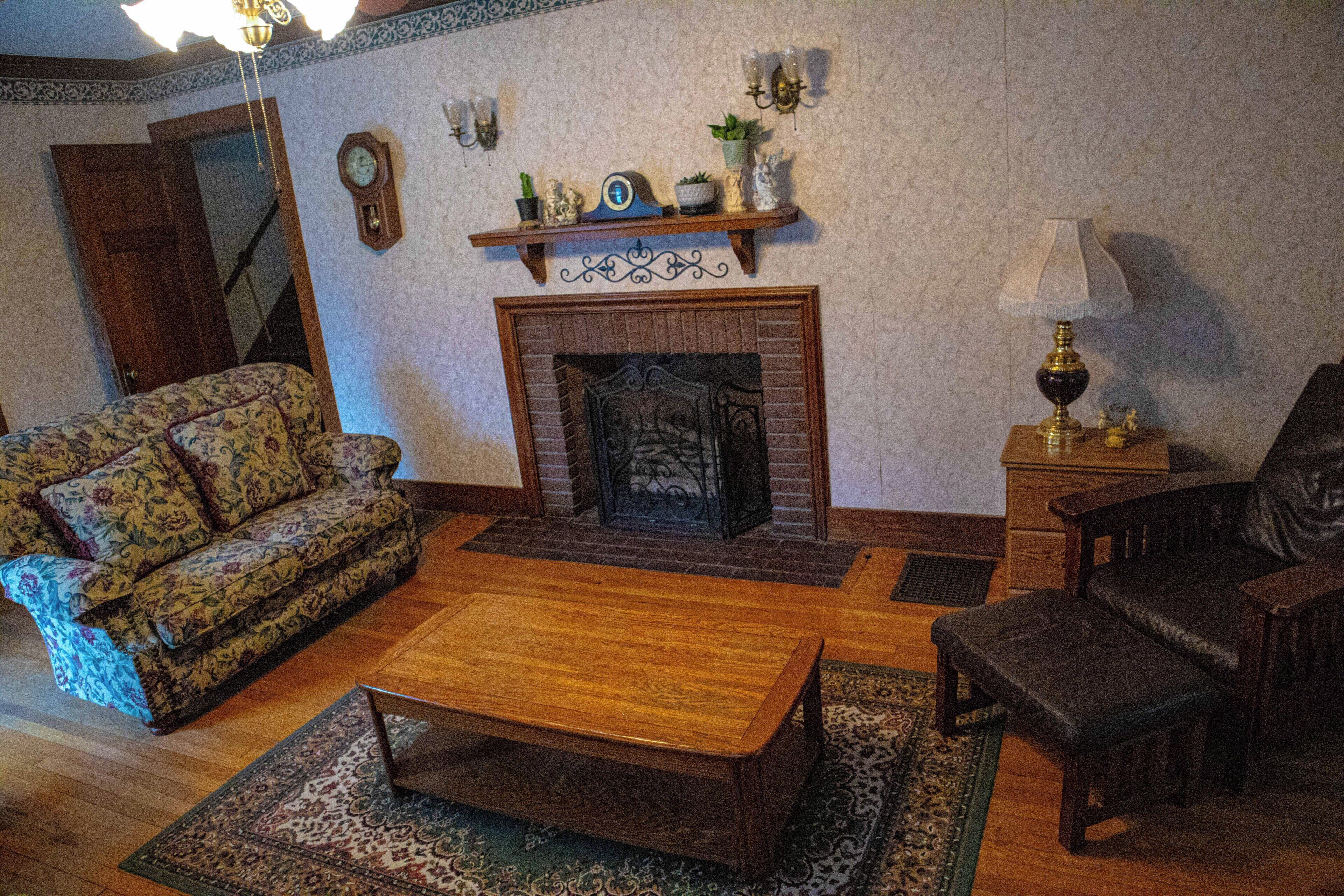 A living room with a fireplace, a sofa, a coffee table, and a chair.