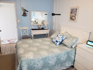 A bedroom with a bed, bedside table, nightstand, and a wall-mounted clock. - OC Md family condo, 19th bdwlk- Sleeps 8, 3 bedroom, 2 bath, Positive reviews. (Ocean City)