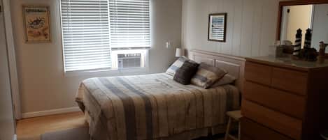 A bedroom with a bed, dresser, window with blinds, and a ceiling fan.
