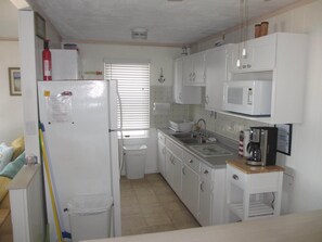 A compact kitchen with white cabinets, a refrigerator, a microwave, and a coffee maker. - OC Md family condo, 19th bdwlk- Sleeps 8, 3 bedroom, 2 bath, Positive reviews. (Ocean City)