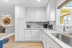 A modern kitchen with white cabinetry, a granite countertop, and a stainless steel sink. - Rod and Reel Haven on Minnow Creek (Hernando Beach)